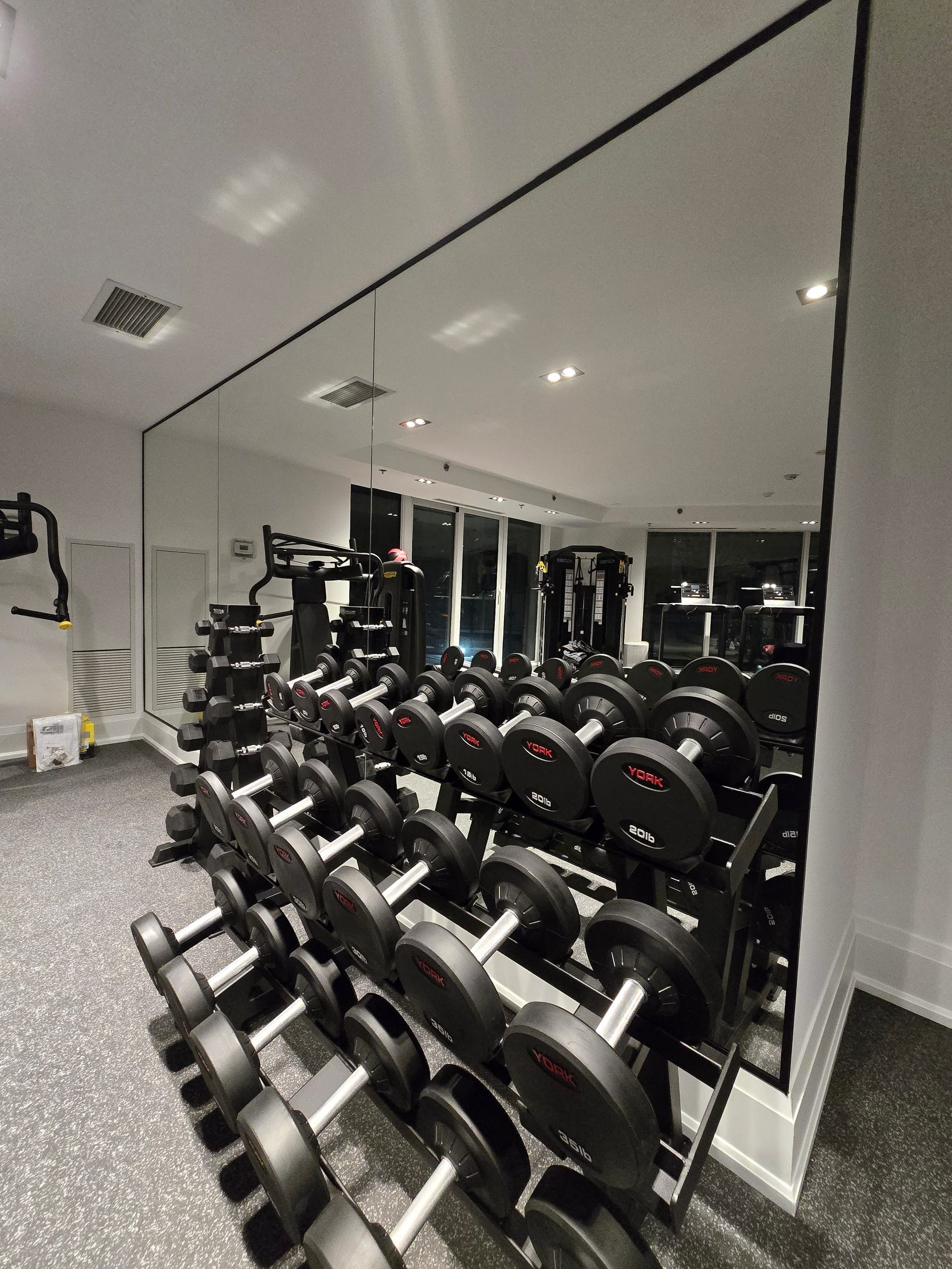 Wall-to-wall safety-backed mirror installation in home gym with full dumbbell rack — Built By Glass GTA