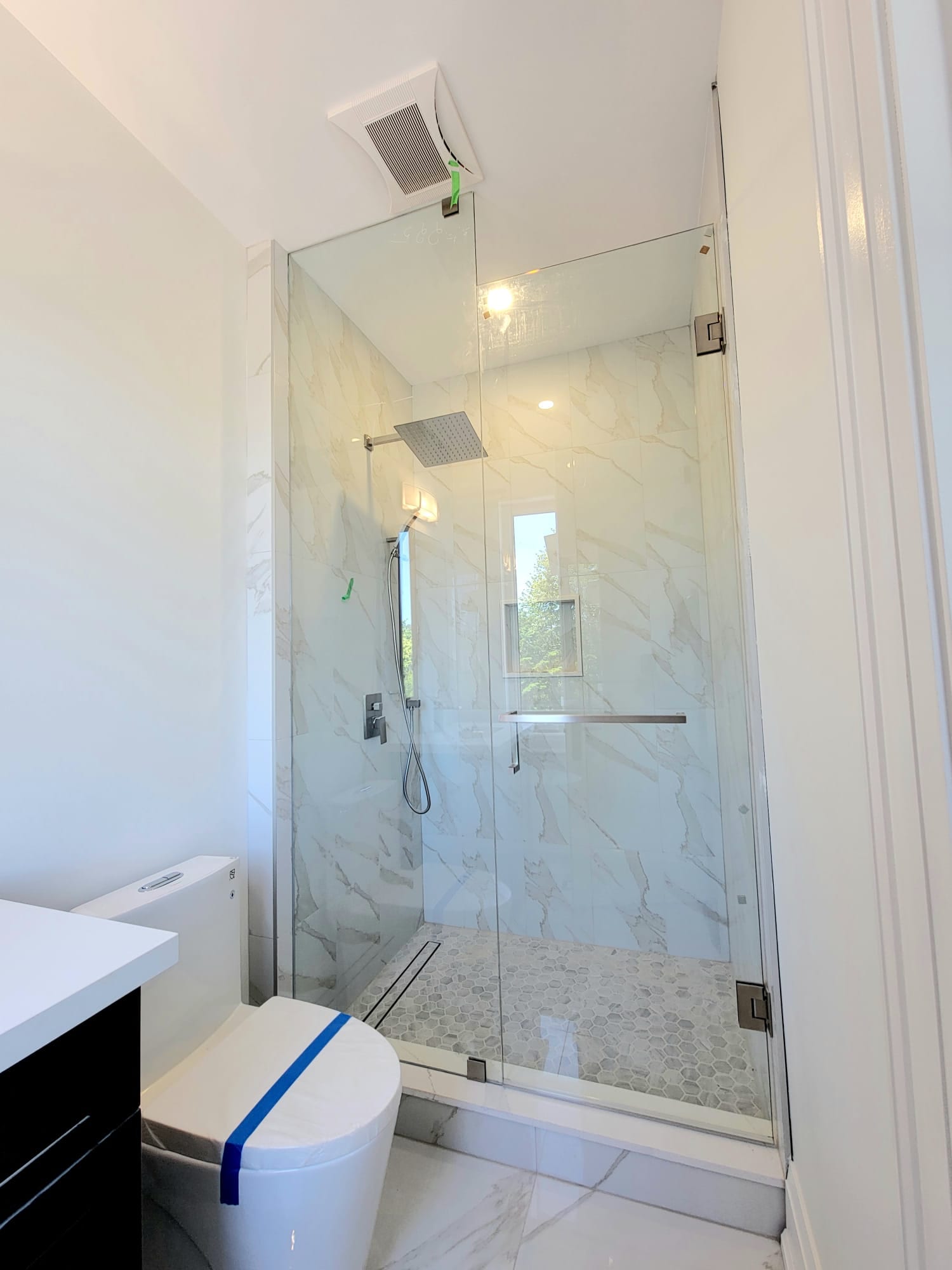 Frameless glass shower with Calacatta-look marble walls and a window niche — Built By Glass