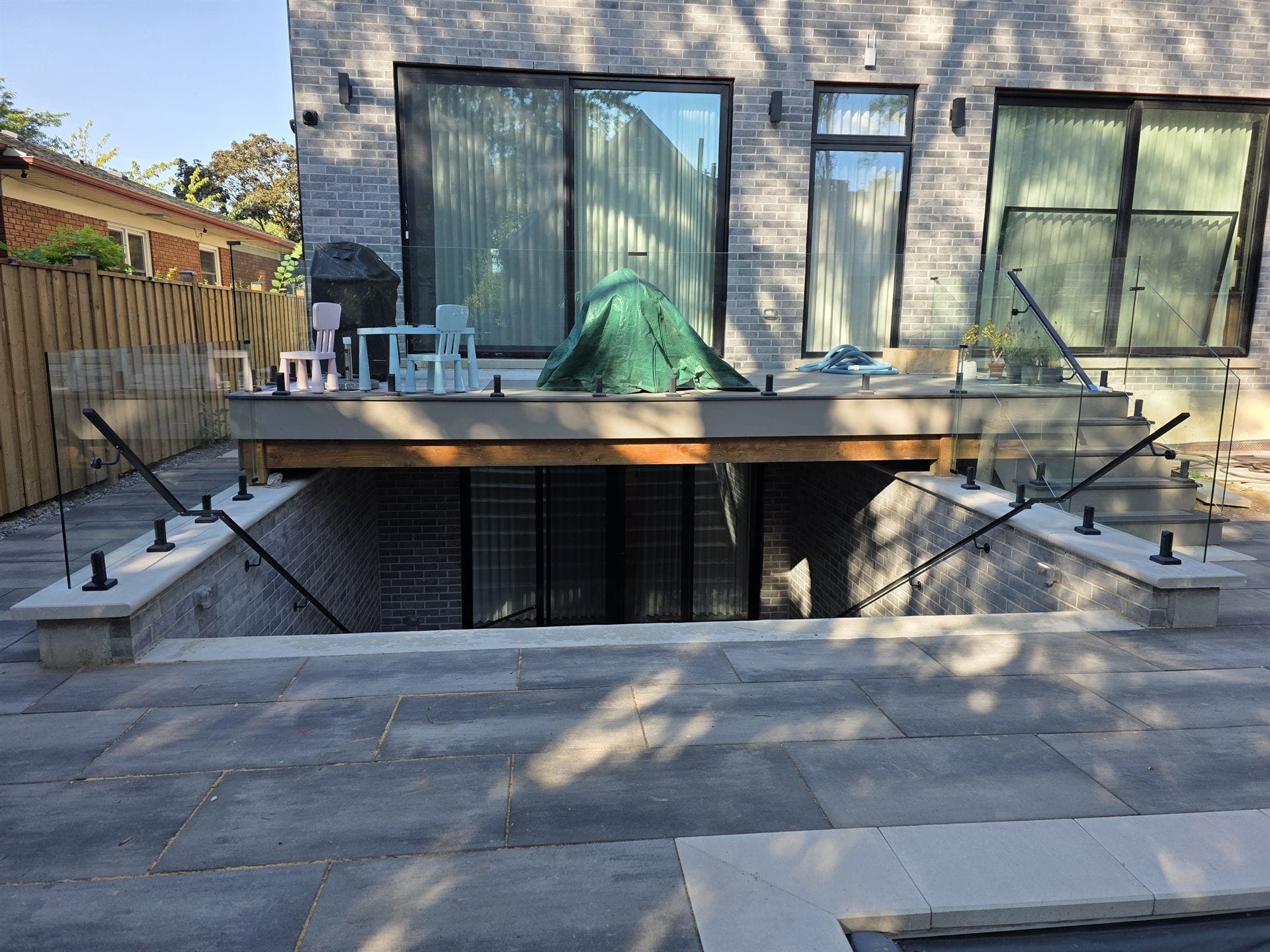 Glass deck railing surrounding sunken patio with built-in bench seating and fire feature — Built By Glass, Burlington